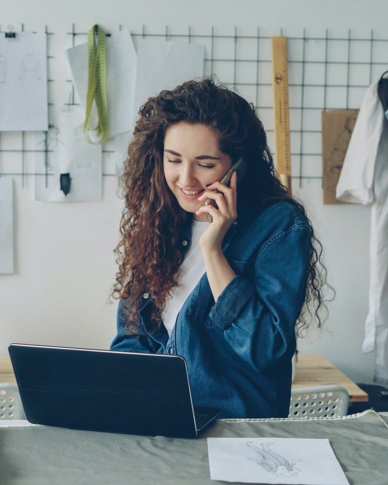 Frau telefoniert am Laptop in ihrem Atelier